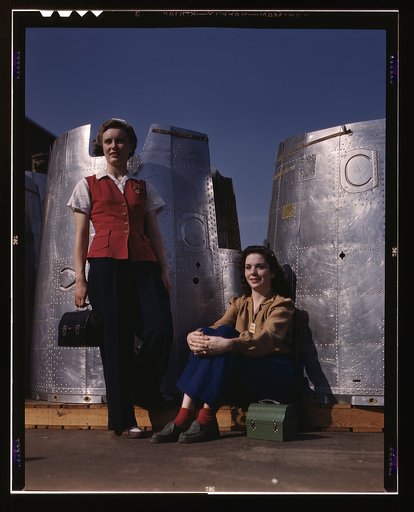 Two assembly line workers at the Long Beach, Calif., plant of Douglas Aircraft Company enjoy a well-earned lunch period, Long Beach, Calif. Nacelle parts of a heavy bomber form the background