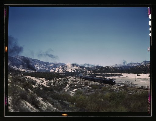 Santa Fe R.R. trains going through Cajon Pass in the San Bernardino Mountains, Cajon, Calif. On the right, streamliner "Chief" going west; in the background, on the left, a freight train with a helper engine, going east. Santa Fe trip
