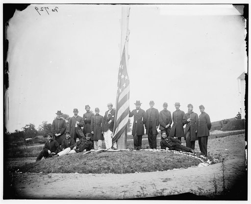 Washington, D.C. Signal Corps officers lowering flag at their camp near Georgetown; Gen Albert J. Myer, in civilian dress, at right of pole