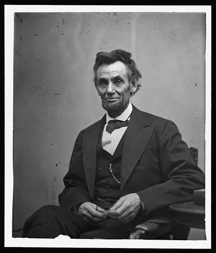 Abraham Lincoln, three-quarter length portrait, seated and holding his spectacles and a pencil