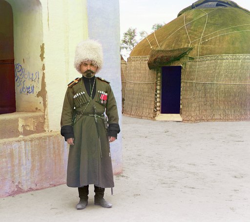 Man in uniform beside building, yurt in background
