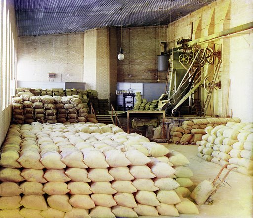 Sacks stacked in storage room, pulley system machinery mounted along wall