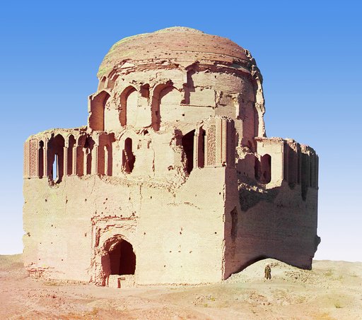 Front view of a crumbling mosque, with a man standing beside it