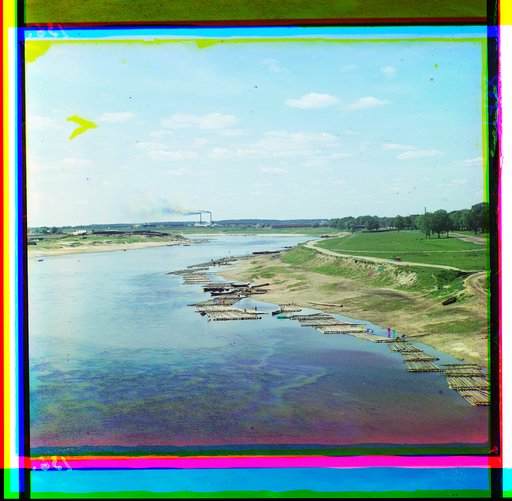 Log rafts along the river. Factory on the horizon