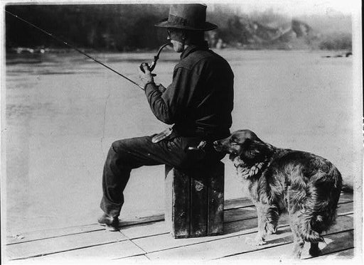 Hooch Hound, a dog trained to detect liquor (as suggested to Commissioner Haynes by a prohibition agent in Colorado), sniffs at flask in back pocket of man, seated, fishing on pier on the Potomac River