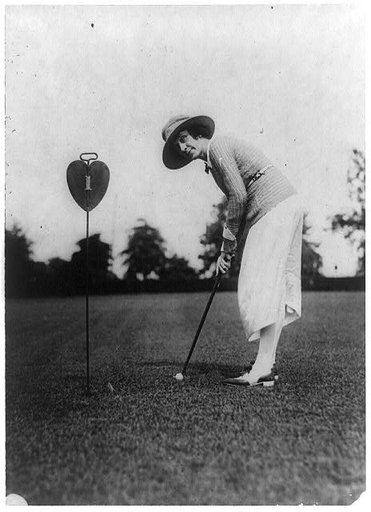 Woman swinging at golf ball close to hole, Washington, D.C., area