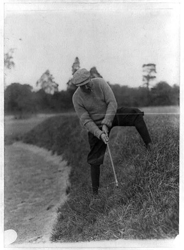 Man swinging at golf ball up hill, Washington, D.C.