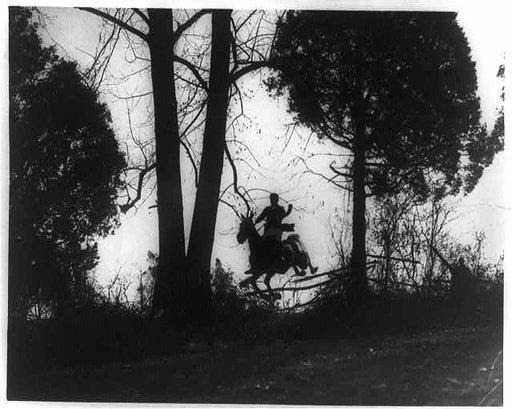 Man on horse jumping fence in fox hunt in Virginia