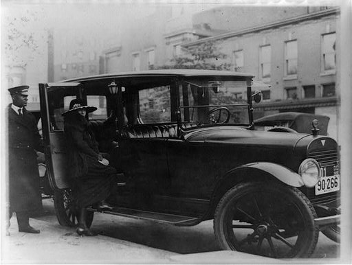 Woman getting into back seat of car as chauffeur holds door, Washington, D.C., area