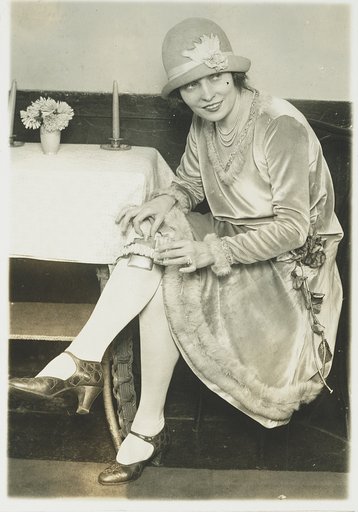 Latest thing in flasks. Mlle. Rhea, dainty dancer who is now in the city as part of the Keiths program inaugurates the garter flask fad in Washington
