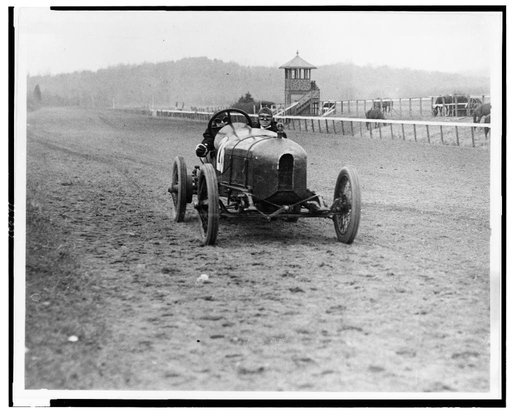 Front view of man and woman riding in Stutz Weightman Special no. 26 on Benning race track, Washington, D.C., area
