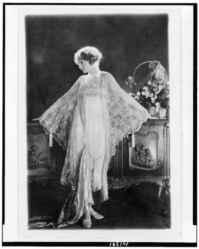 Lillian Gish, full-length portrait, standing, facing left, wearing pink morning gown of chiffon and lace