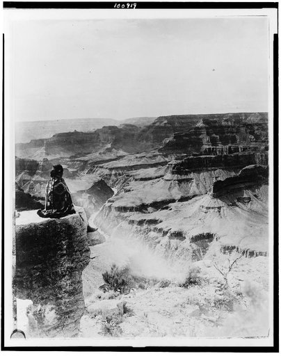 Native American seated on the edge of the Grand Canyon, Arizona