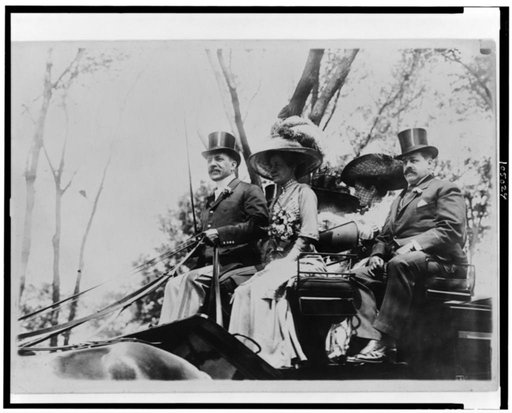 Harris Charles Fahnestock seated in carriage next to woman in plumed hat (possibly his wife) with another couple at the back of the carriage