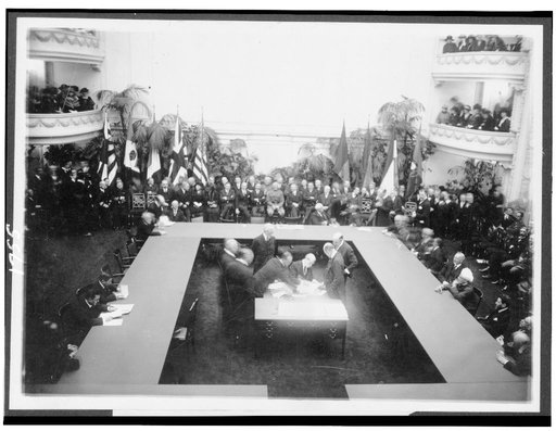 Secty of State Hughes signing the treaties resulting from the Conference of Limitation of Armaments today. Other members of the American delegation around the table