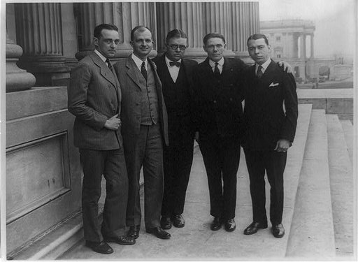 Five men, one in middle with glasses, posed standing on steps of the U.S. Capitol