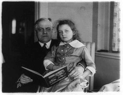 Alexander Mitchell Palmer, three-quarter-length portrait, seated facing front, with girl on his lap, holding book