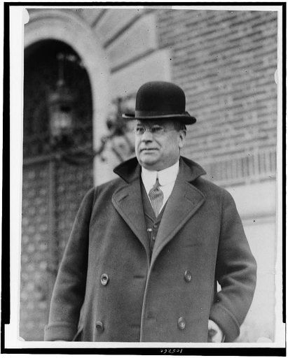 Hiram W. Johnson, half-length portrait, standing, facing left, wearing bowler hat