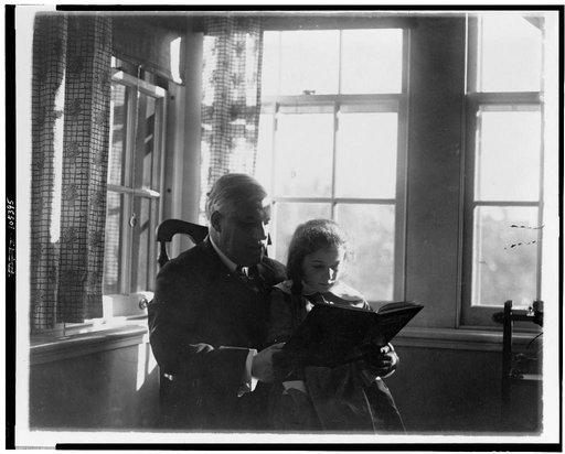 Alexander Mitchell Palmer, half-length portrait, seated, facing right, reading to girl seated on his lap