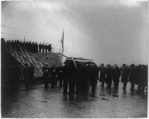 Military funerals at Arlington National Cemetery--flag-draped casket, unloaded from ship, being carried by sailors and marines