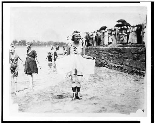 Young woman posing in bathing suit with other bathers and spectators in background