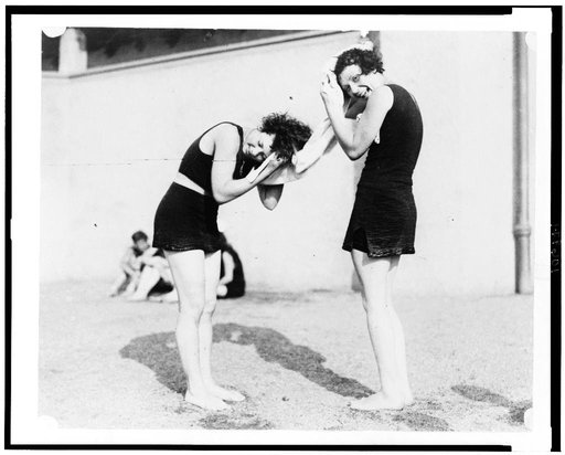 Two women in bathing costumes drying their hair