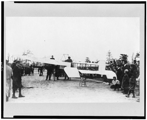 Louis Blériot(?) on his airplane, surrounded by people