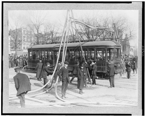Firemen with hoses over streetcar