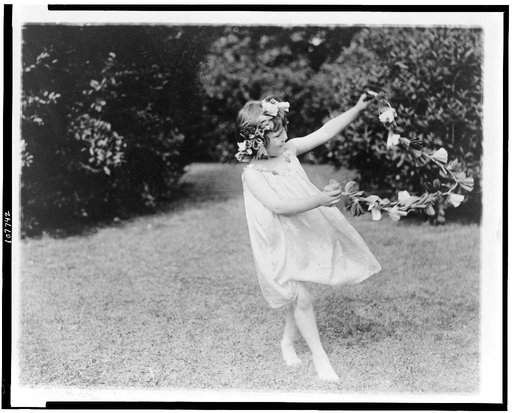 Girl, with flowers in hair, holding flower garland