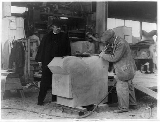 Bishop James E. Freeman watching a stone cutter of the George A. Fuller Co. put the finishing touches on a section of the base for the National Cathedral on Mount Saint Alban