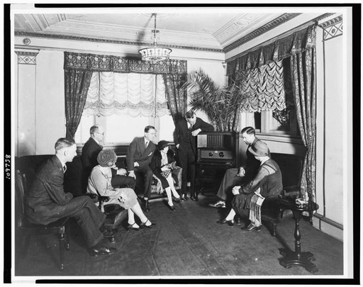 Atwater Kent, standing by radio, and seven other people listening to the radio, in the Hamilton Hotel, Washington, D.C.