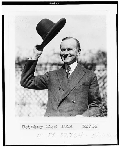 Calvin Coolidge, half-length portrait, standing, facing left, tipping his hat