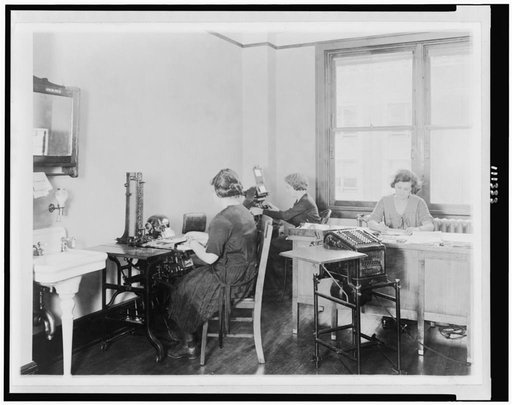 Three young women at work in an unidentified Washington, D.C. office. The girl at the left is operating an addressograph