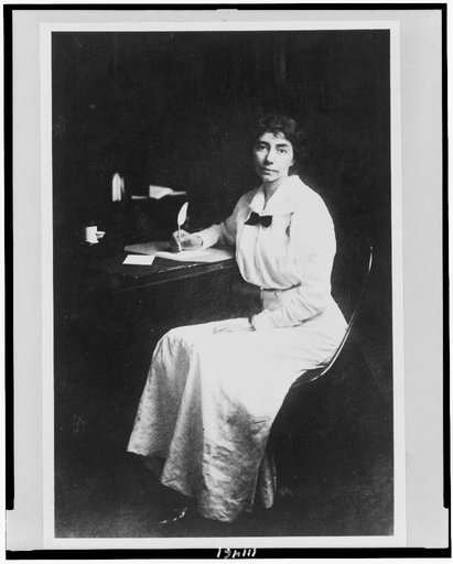 Madeline Breckinridge, full-length portrait, seated at desk, facing slightly left, with quill pen in hand