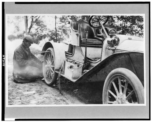 Man fixing tire on a Buick roadster outside of Liberty, on a trip through upstate New York