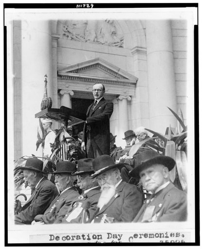 President Coolidge three-quarter length portrait, standing at podium, facing slightly left, at Decoration Day ceremonies, Arlington