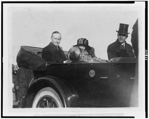 President and Mrs. Coolidge and unidentified man riding in convertible automobile
