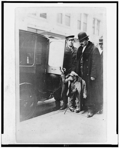 Chimpanzee in clothing at door of automobile, with three men, at Napoleon Hippodrome