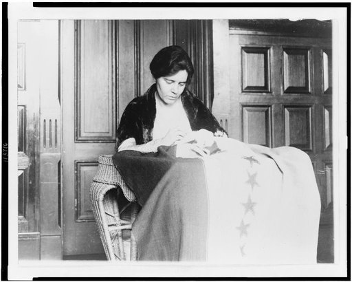 Miss Alice Paul is shown sewing the thirty-sixth star on the suffrage ratification banner, the stars having been added from time to time as the various states ratified