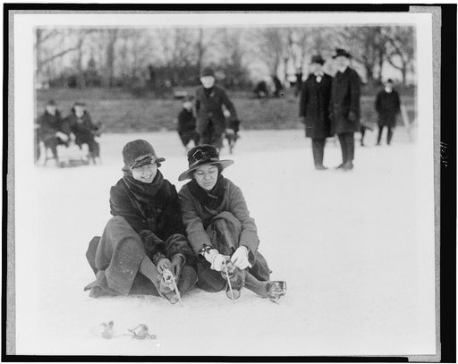 Two people seated on snow, and putting on ice skates, in the Washington, D.C., area