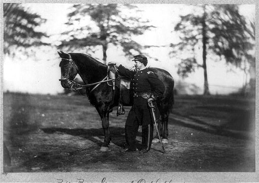 O.H. Hart, full-length portrait, standing, left profile, in uniform, alongside horse
