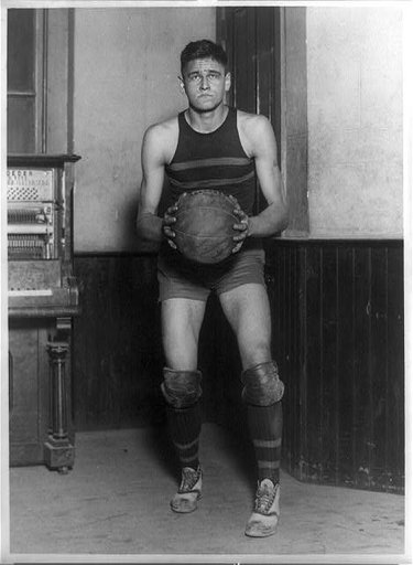 John Loebler, center on George Washington University basketball team, standing, full-length portrait, holding basketball