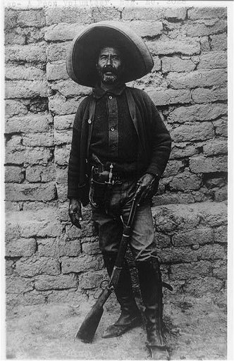 Mexico - a peón volunteer [standing in front of wall and holding a rifle