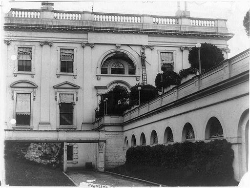 Two workmen clearing cobwebs from exterior of the White House