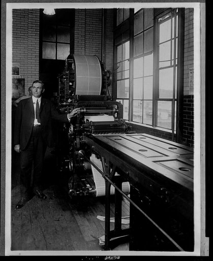 Benjamin R. Stickney standing next to a postage stamp printing machine, which he revolutionized, in the Bureau of Engraving and Printing