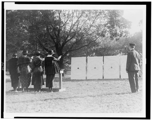 Four policewomen shooting at targets, as a policeman watches