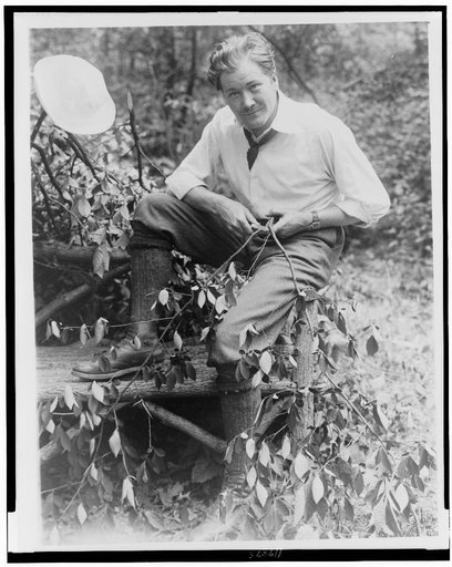 John Charles Thomas, singer, full-length portrait, sitting on log bench, whittling a small branch
