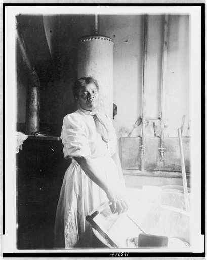 African American woman, three-quarter length portrait, standing, facing front, doing laundry at wash tub, in Washington, D.C. or New York