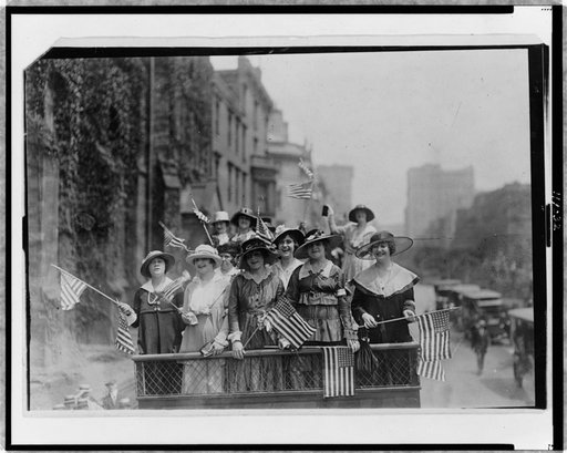 Group of women standing on top of vehicle waving flags, New York City