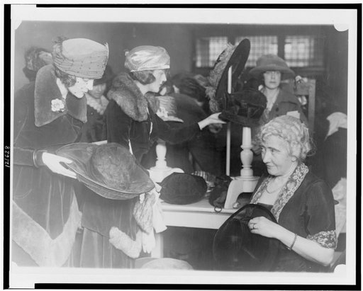 Mrs. Lawrence Townsend at the fourth annual rummage sale of the Child Welfare Society trims discarded hats for the price of one year's milk supply for a Washington baby
